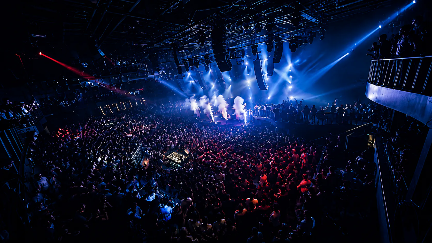 A packed Club Nova dance floor beneath blue and red stage lights